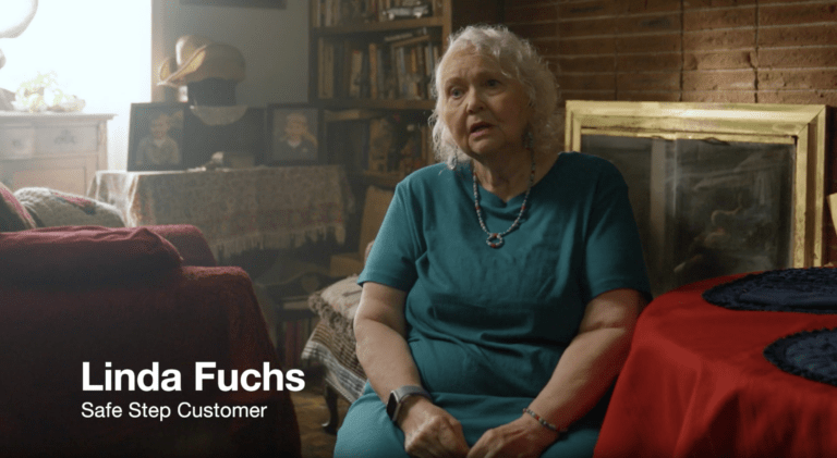 A woman named Linda sits in her living room on a red armchair